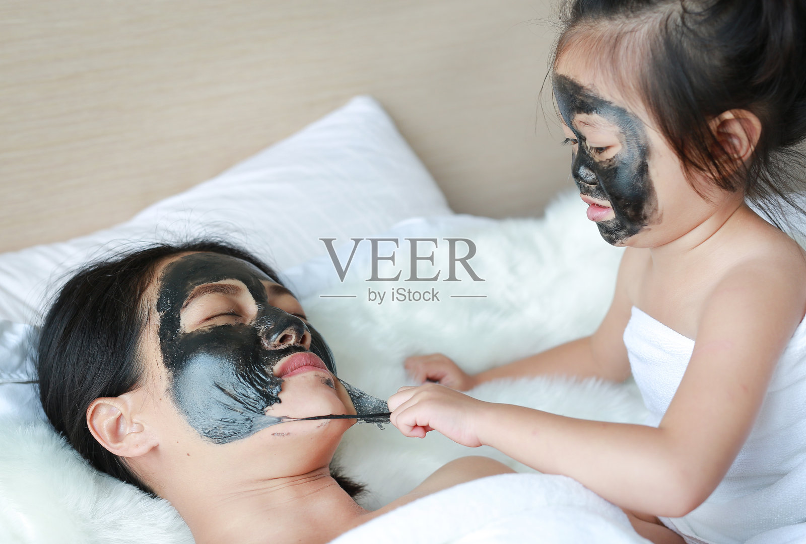 小女孩摘下母亲的黑色面具，洗干净了脸。照片摄影图片