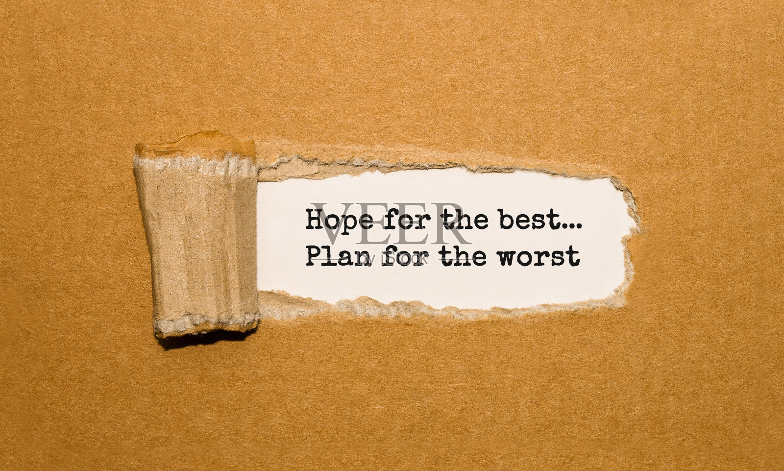 “抱最好的希望，做最坏的打算”这句话出现在撕破的牛皮纸后面照片摄影图片