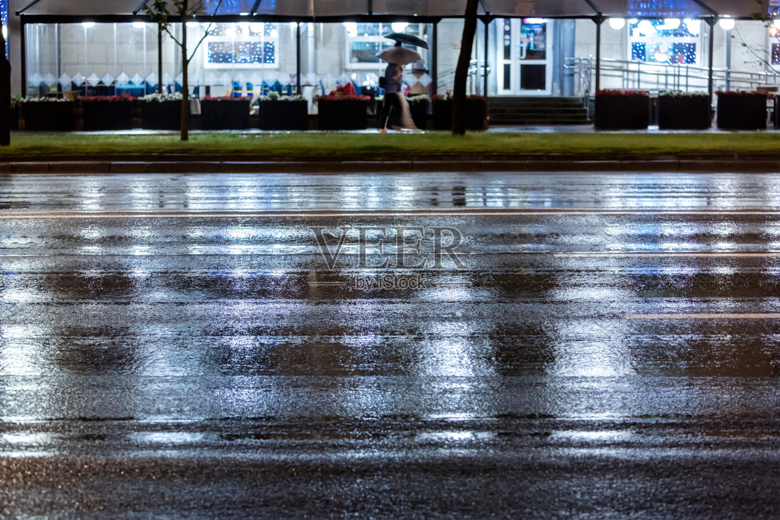 人们在雨夜走在人行道上。模糊的形象。照片摄影图片
