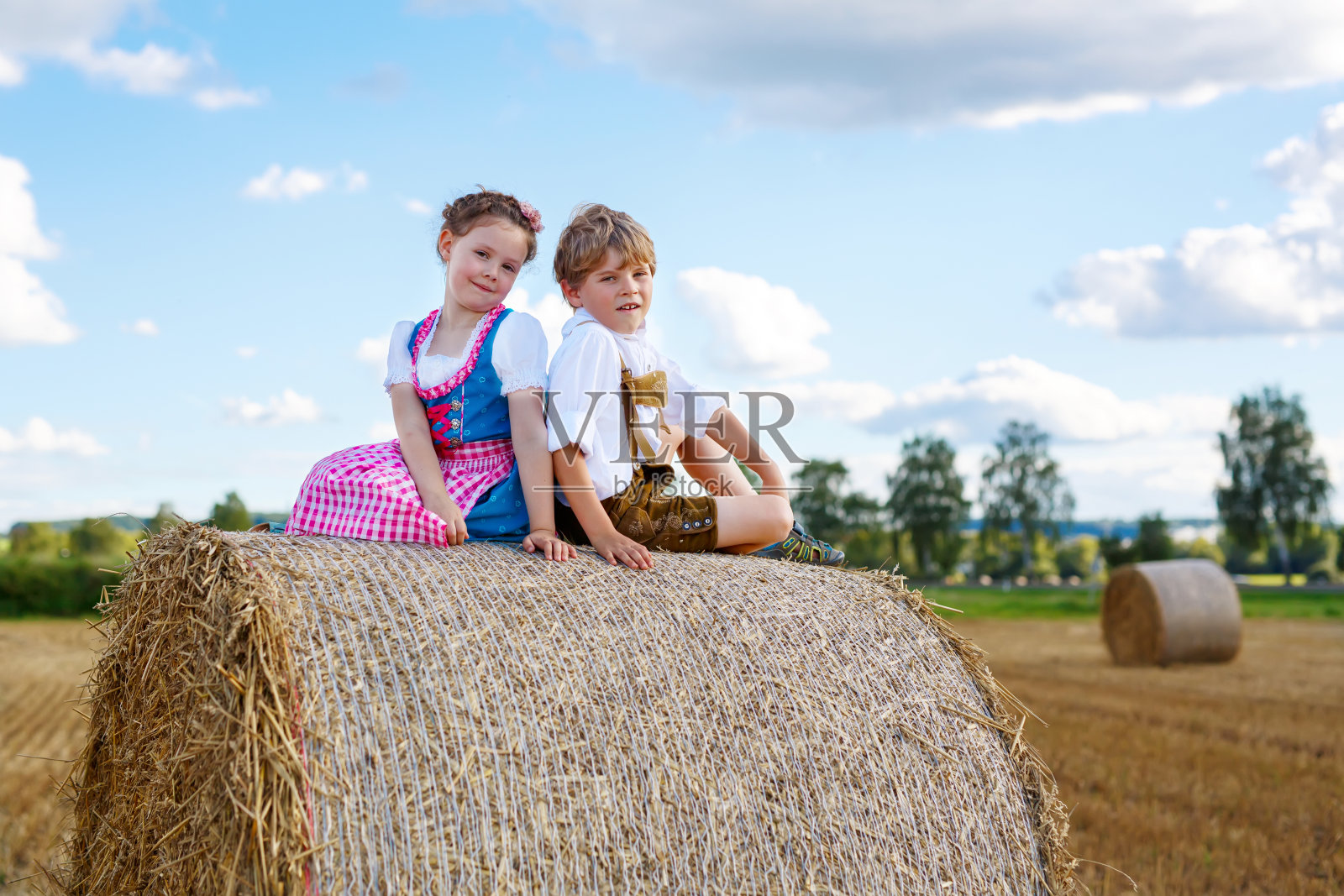 两个孩子，男孩和女孩穿着传统的巴伐利亚服装在麦田里照片摄影图片