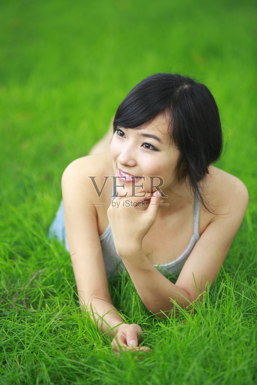 一个年轻漂亮的亚洲女人躺在新鲜的草地上照片摄影图片