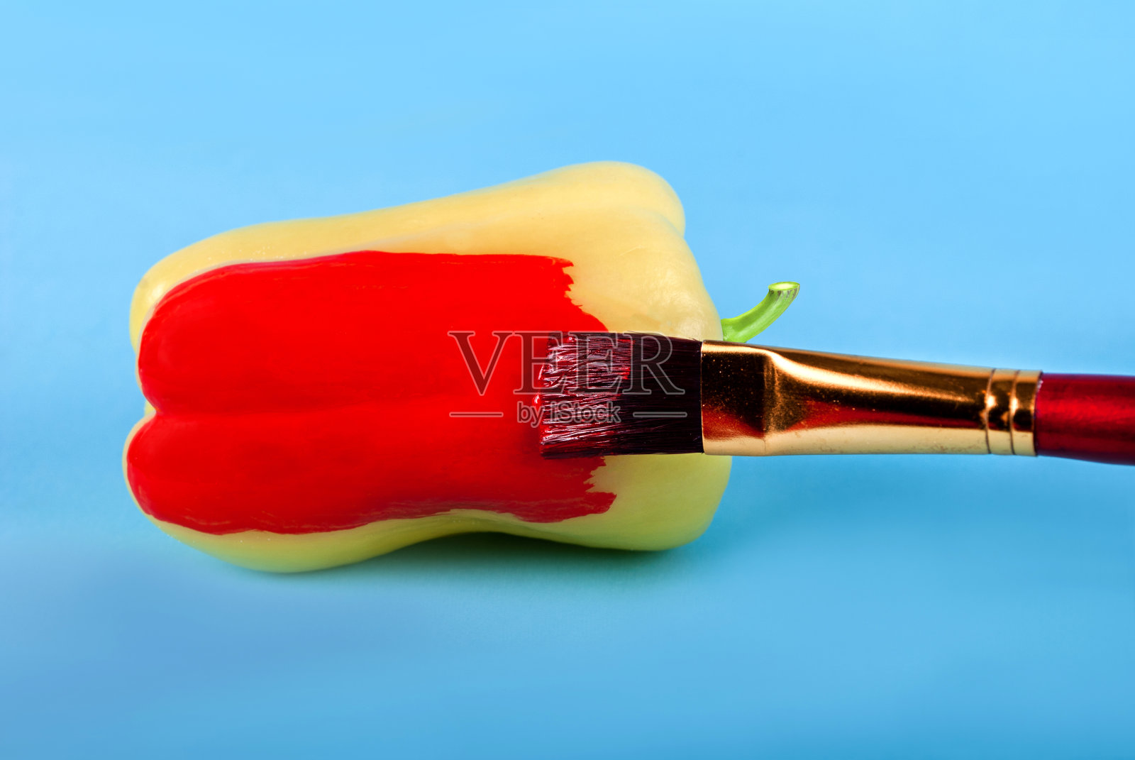 用笔刷把青椒涂成红色，在蓝色的背景上画上坏食物的概念照片摄影图片