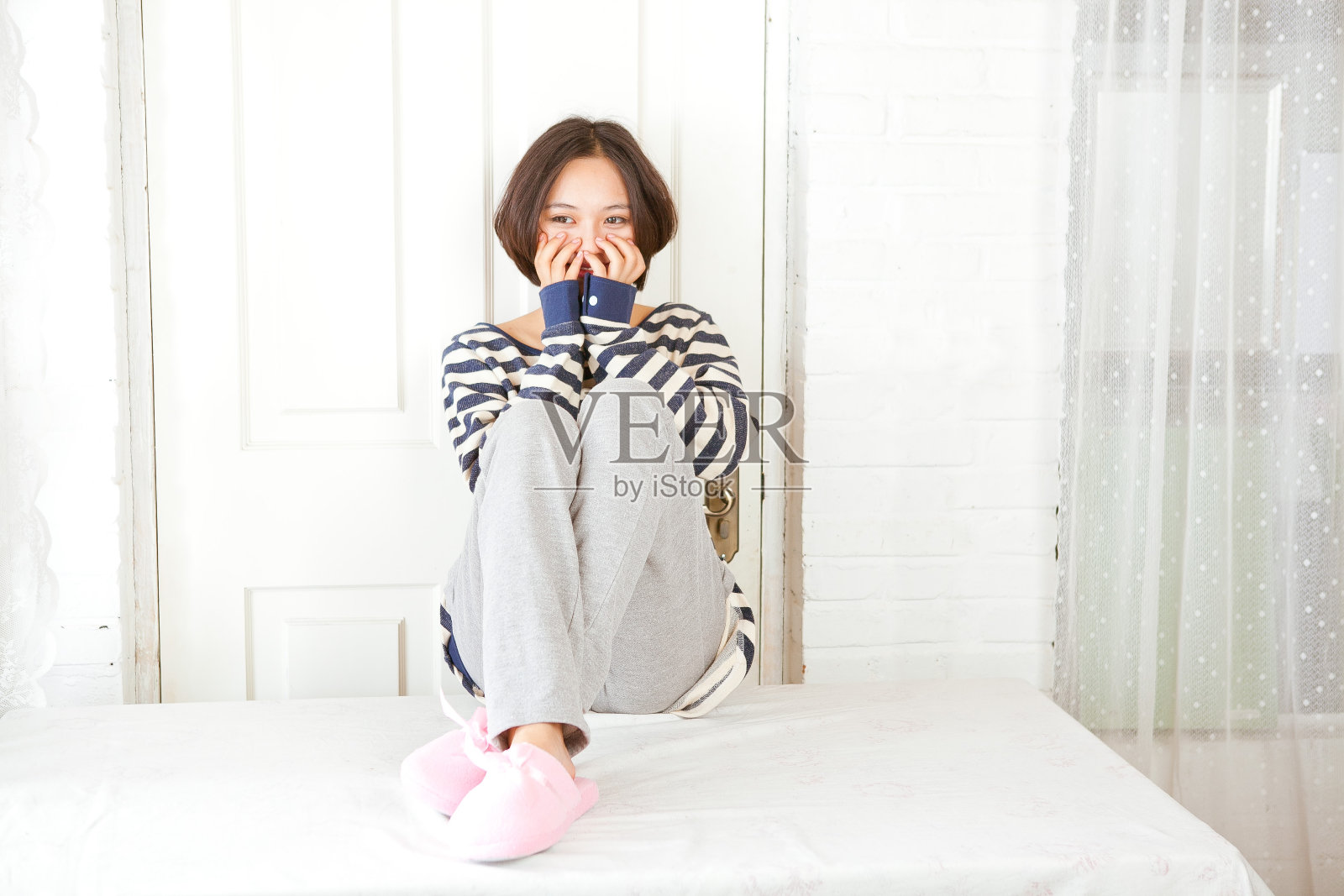 美丽的亚洲女孩坐在床上照片摄影图片