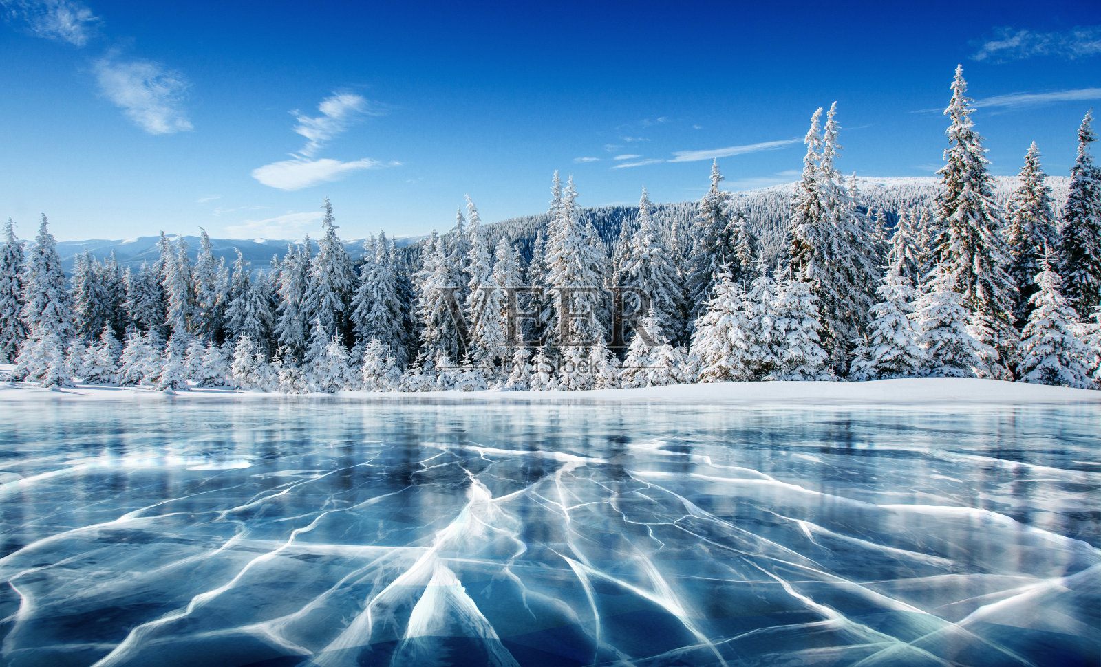 蓝色的冰和冰表面的裂缝。冬天蓝天下的冰湖。松树山。冬天。喀尔巴阡、乌克兰、欧洲。照片摄影图片