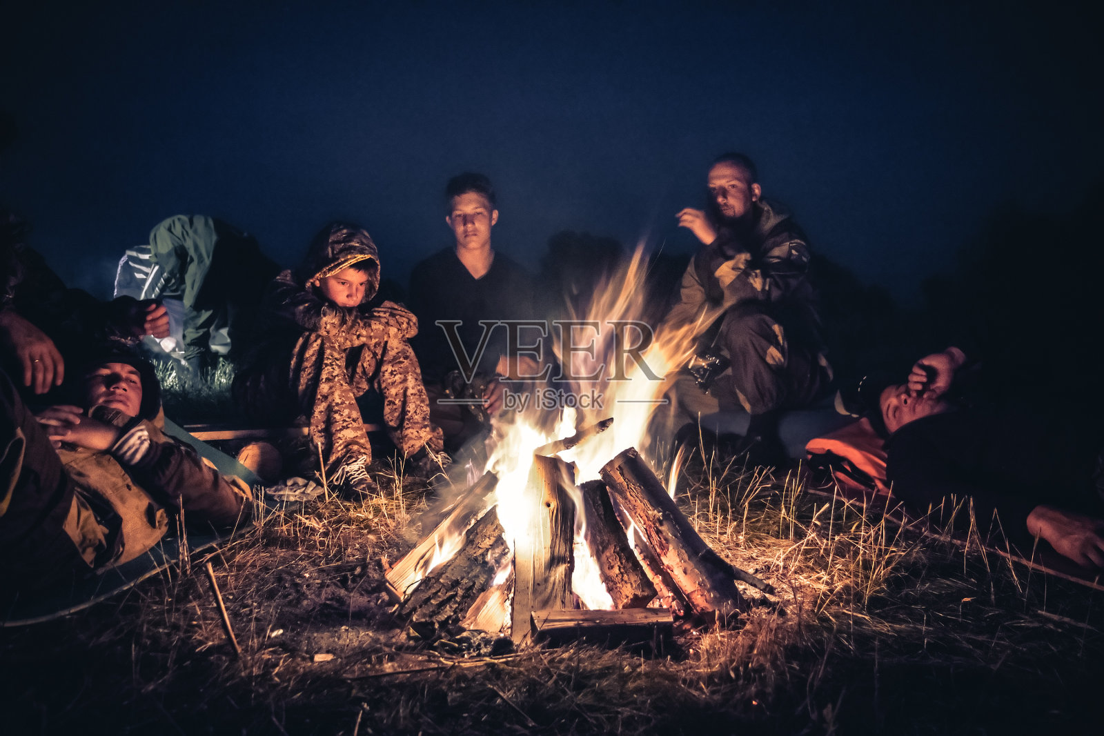 一群探险者在户外营地的火堆旁休息，在漫长的徒步旅行后的夜晚照片摄影图片