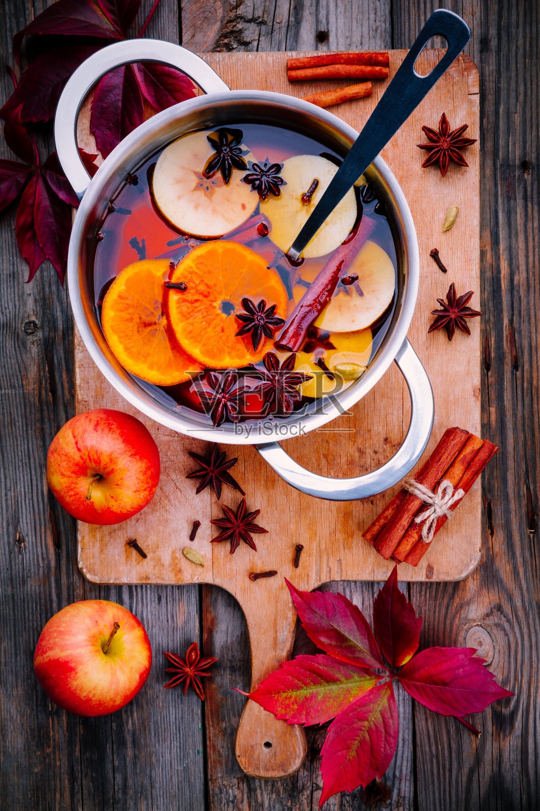 热葡萄酒饮料与柑橘，苹果，肉桂棒，丁香和茴芹在烹饪锅照片摄影图片
