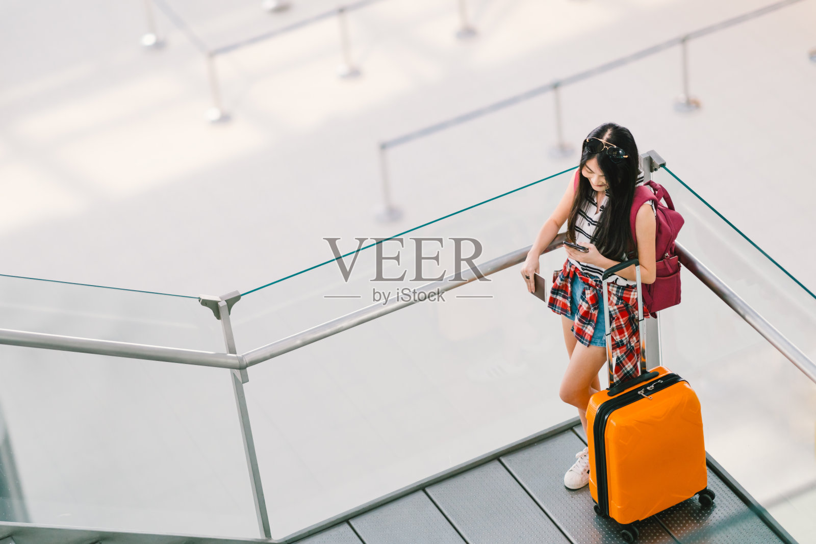 可爱的亚洲少女，大学生在机场拿着行李和背包用智能手机打电话或聊天。网上签到、孤独旅游出国留学、国际旅游生活理念。照片摄影图片