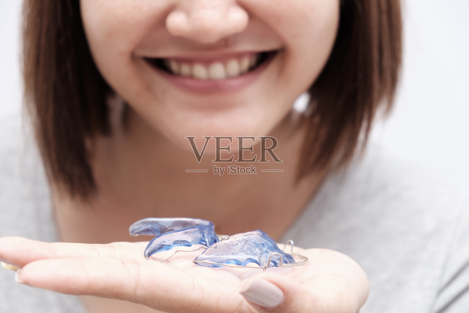 美丽的亚洲女人微笑幸福的手牵手蓝色的固定器。牙齿的牙套。口腔正畸牙齿的主题照片摄影图片