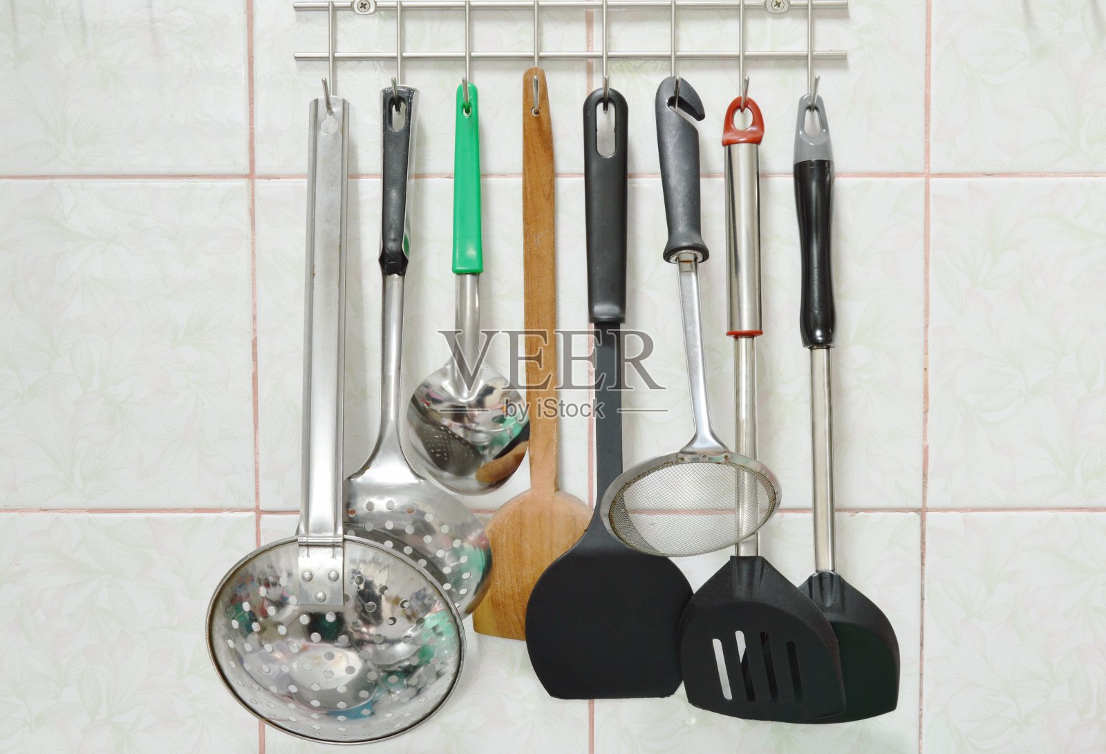 包瓣和滤锅与其他厨房用具移动在不锈钢衣架上照片摄影图片
