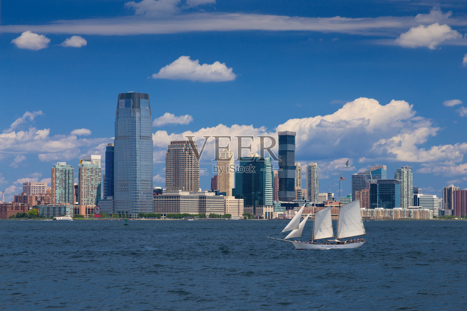 泽西城天际线与高盛大厦，水的纽约港，帆船(高船)和蓝天。照片摄影图片