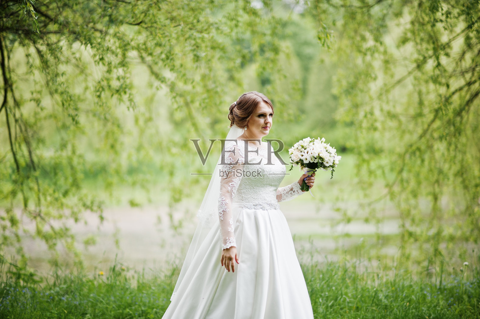 一个美丽的年轻新娘摆姿势与她自己的一束户外的肖像。照片摄影图片