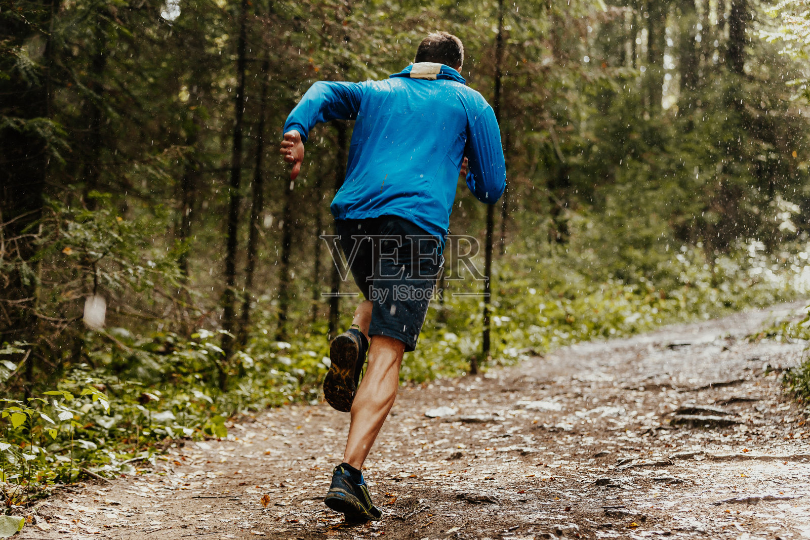肌肉发达的男性跑步者在雨中快速奔跑森林小径照片摄影图片