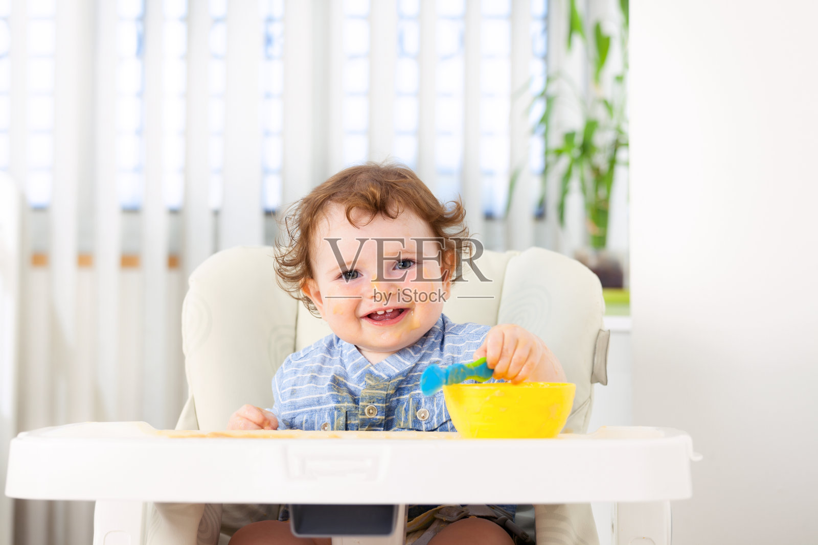 可爱的小男孩独自坐在高椅子上吃东西照片摄影图片