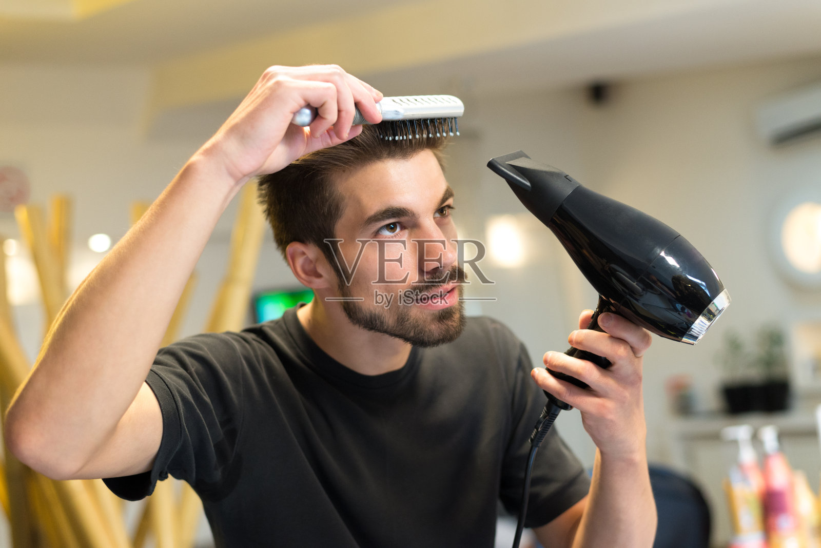 英俊的理发师在美发沙龙梳理他的头发照片摄影图片
