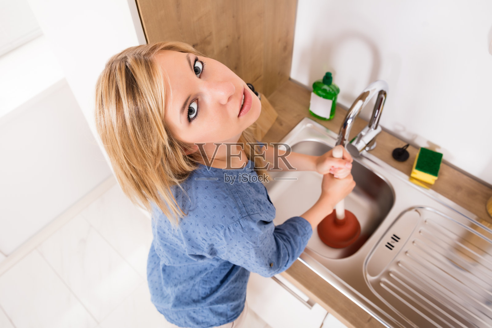 可悲的女人在厨房水槽里用活塞照片摄影图片