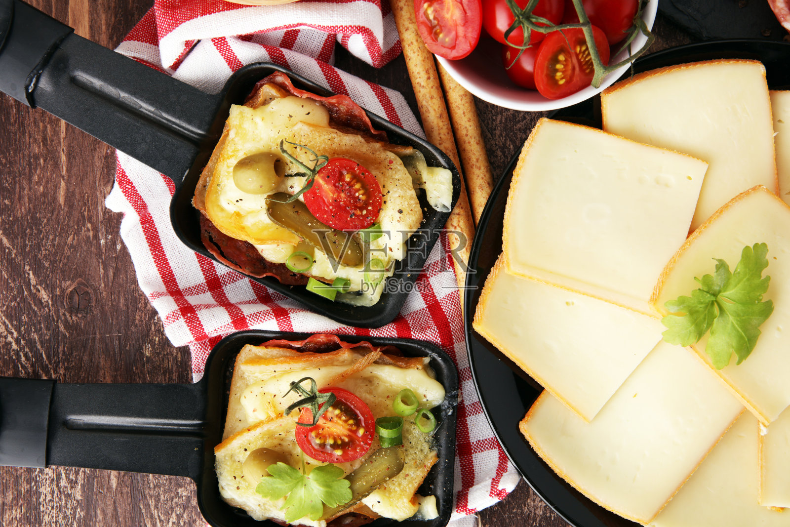 美味的传统瑞士融化的raclette奶酪配煮或烤马铃薯丁，搭配意大利腊肠照片摄影图片