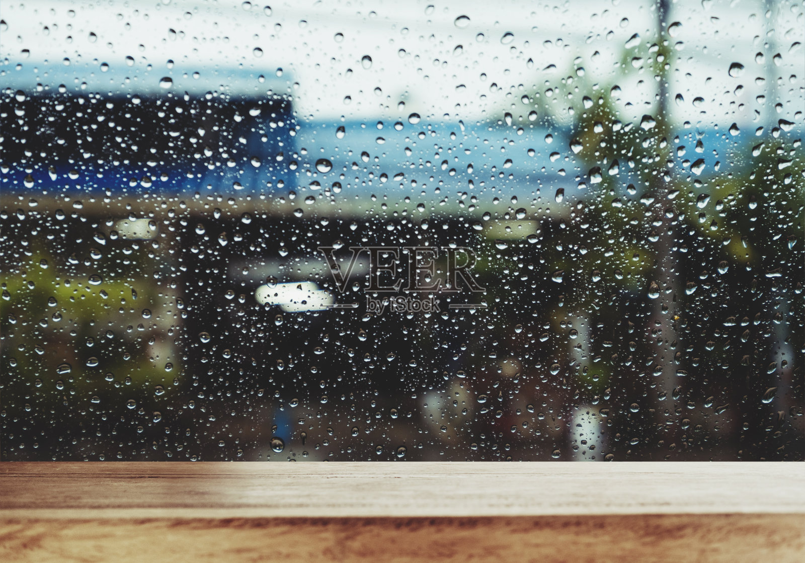 雨天的窗户上有雨滴的木头桌子，作为背景照片摄影图片