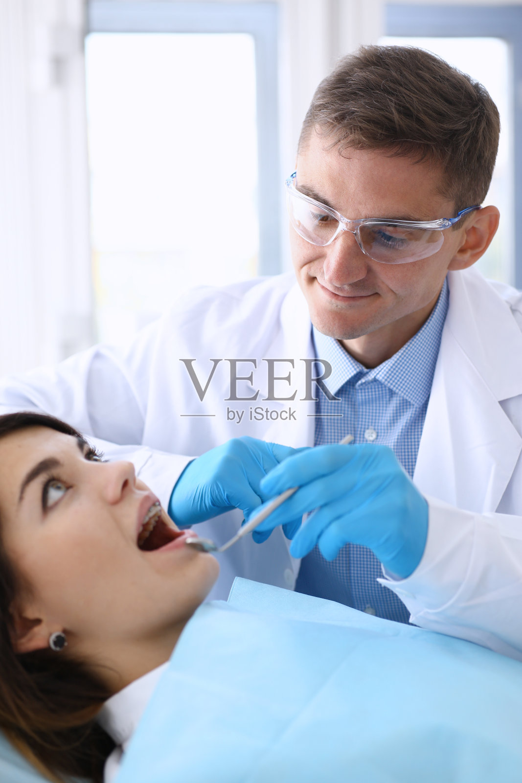 接待一位正在检查牙齿的男牙医的女士照片摄影图片