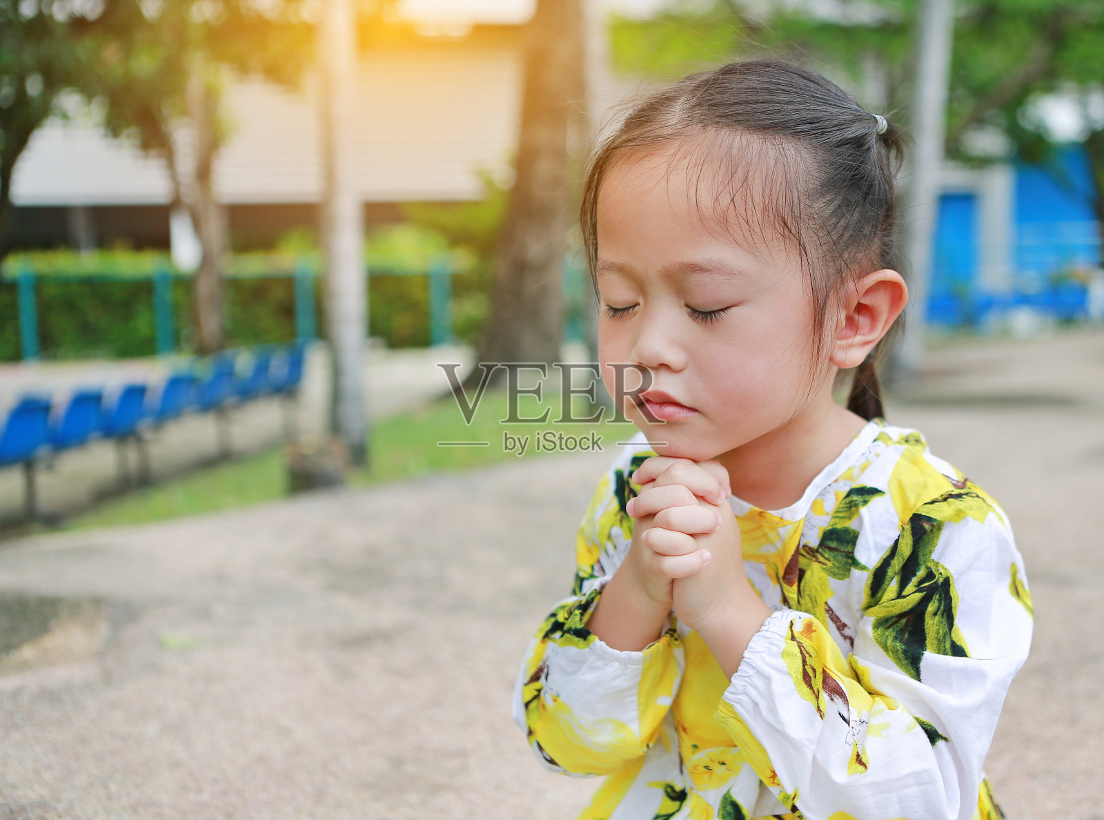 可爱的亚洲小女孩在花园里祈祷。照片摄影图片