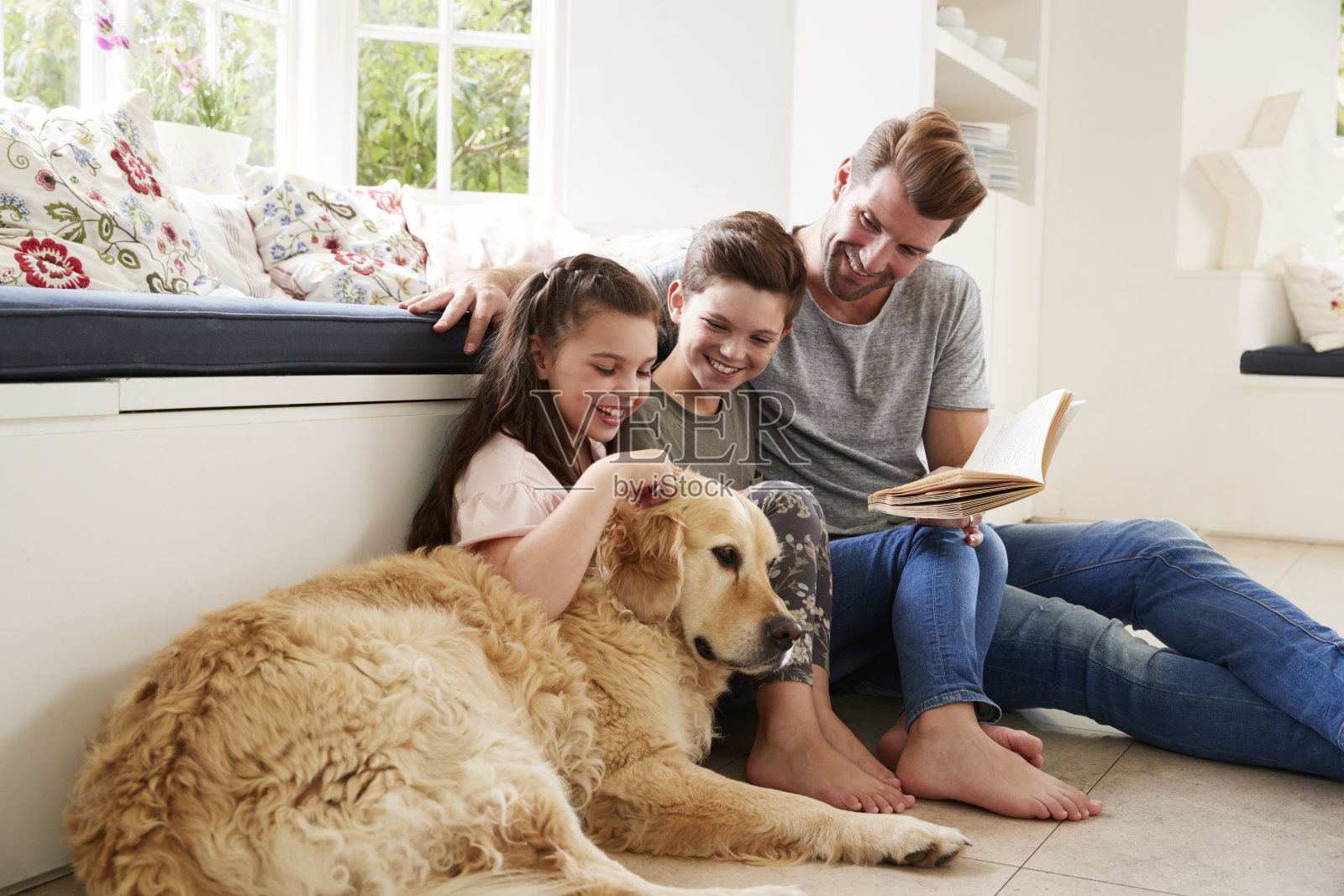 父亲和儿子、女儿、宠物狗在家里读书照片摄影图片