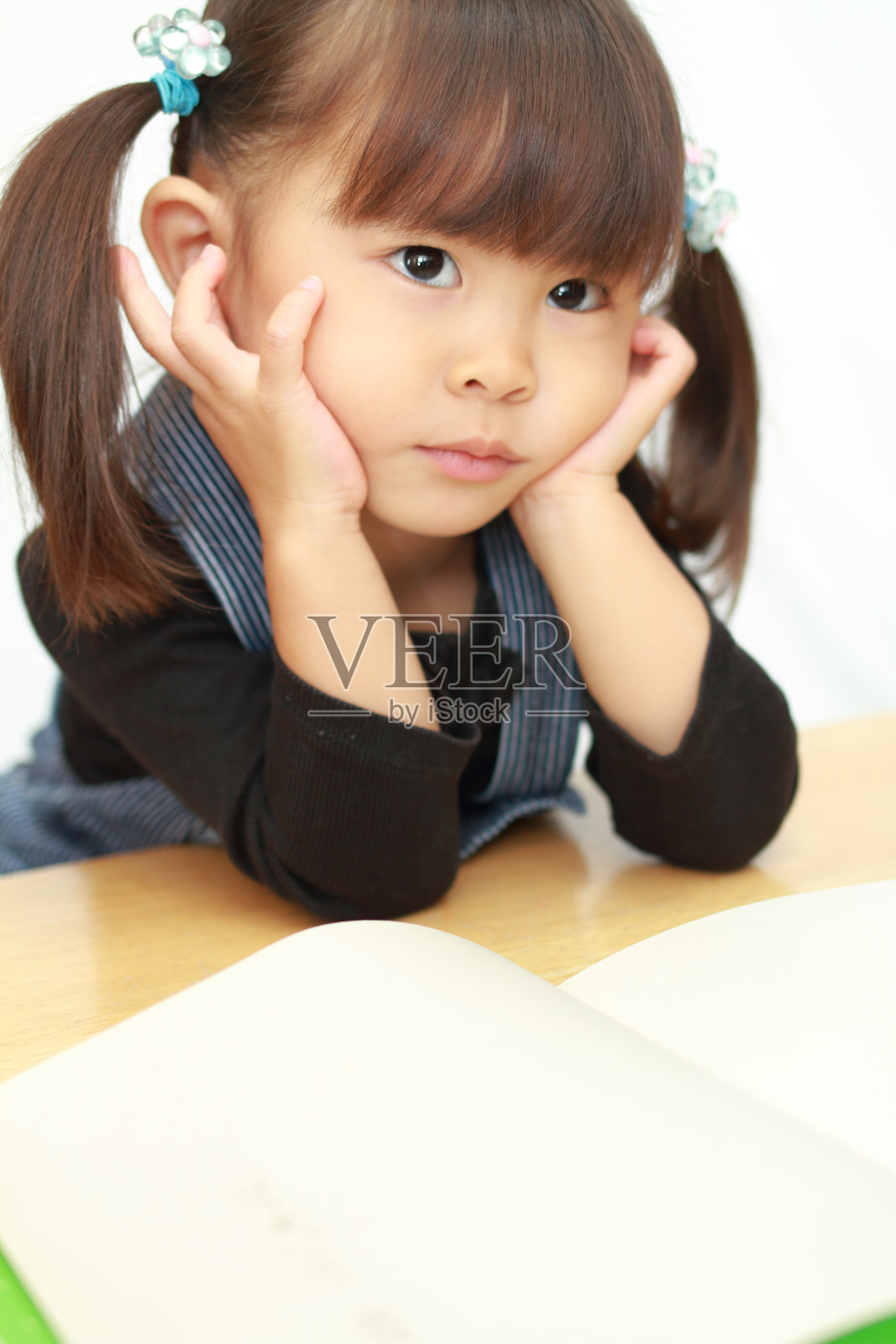 日本女孩手托下巴在看图画书(3岁)照片摄影图片