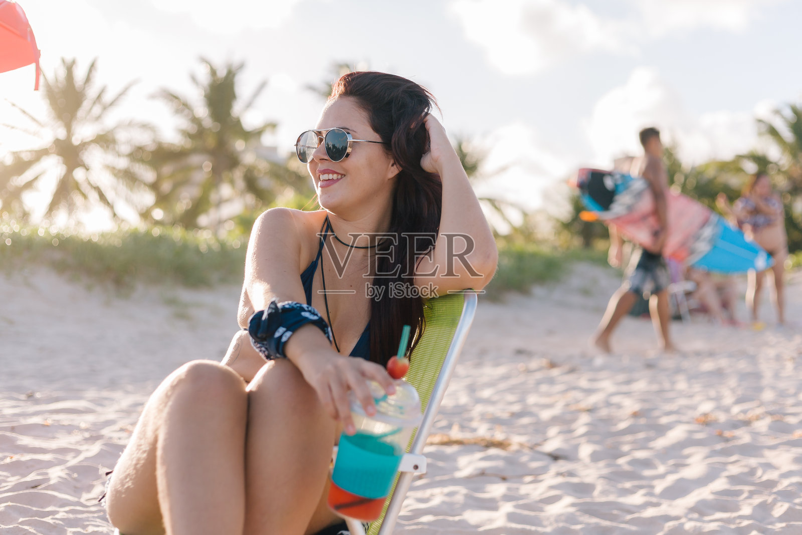 年轻的红发女人在海滩上喝着草莓鸡尾酒照片摄影图片