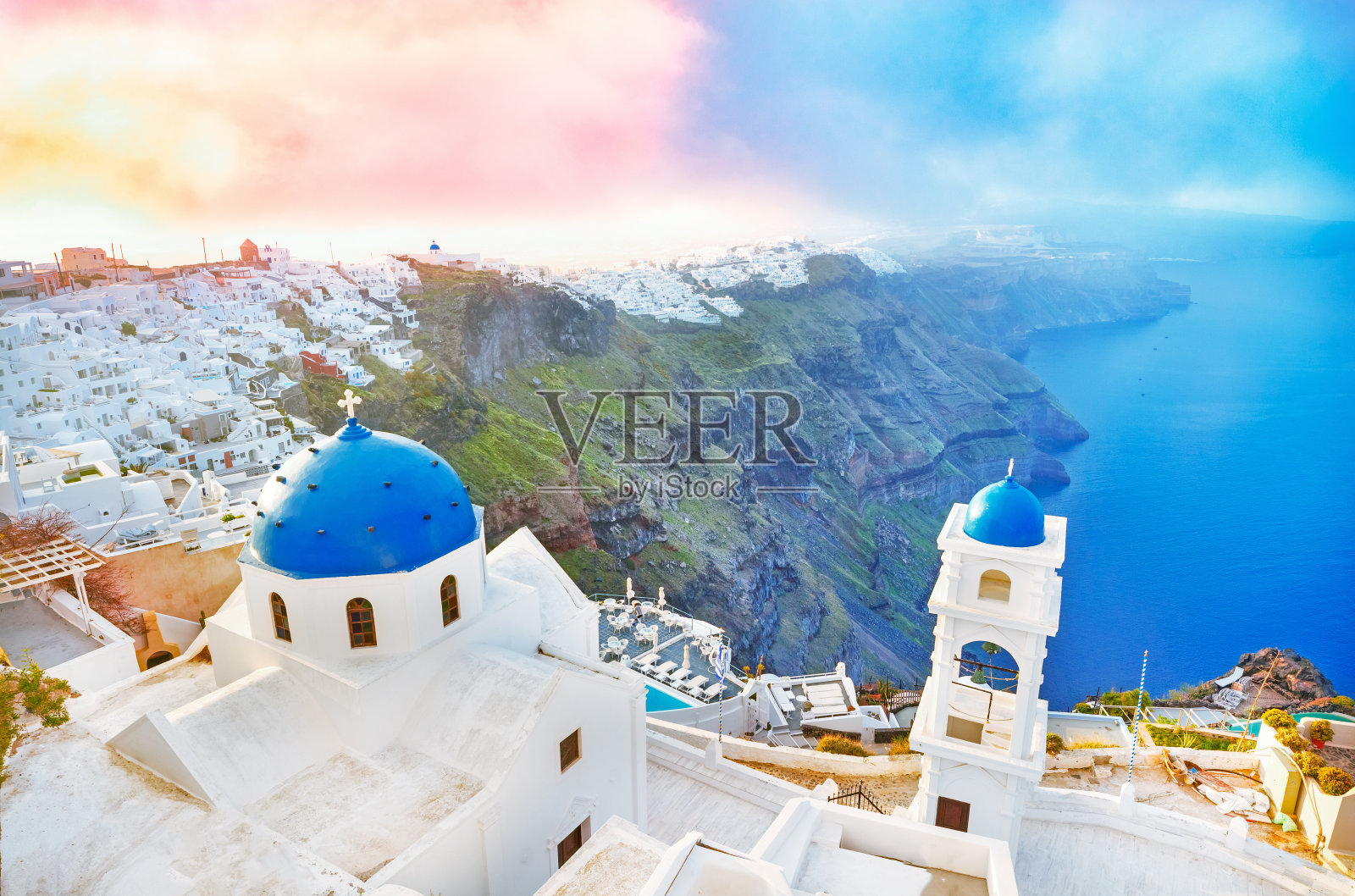 希腊，爱琴海的圣托里尼岛。令人惊叹的黎明景色与蓝色圆顶教堂的前景和史诗日出天空的背景。照片摄影图片