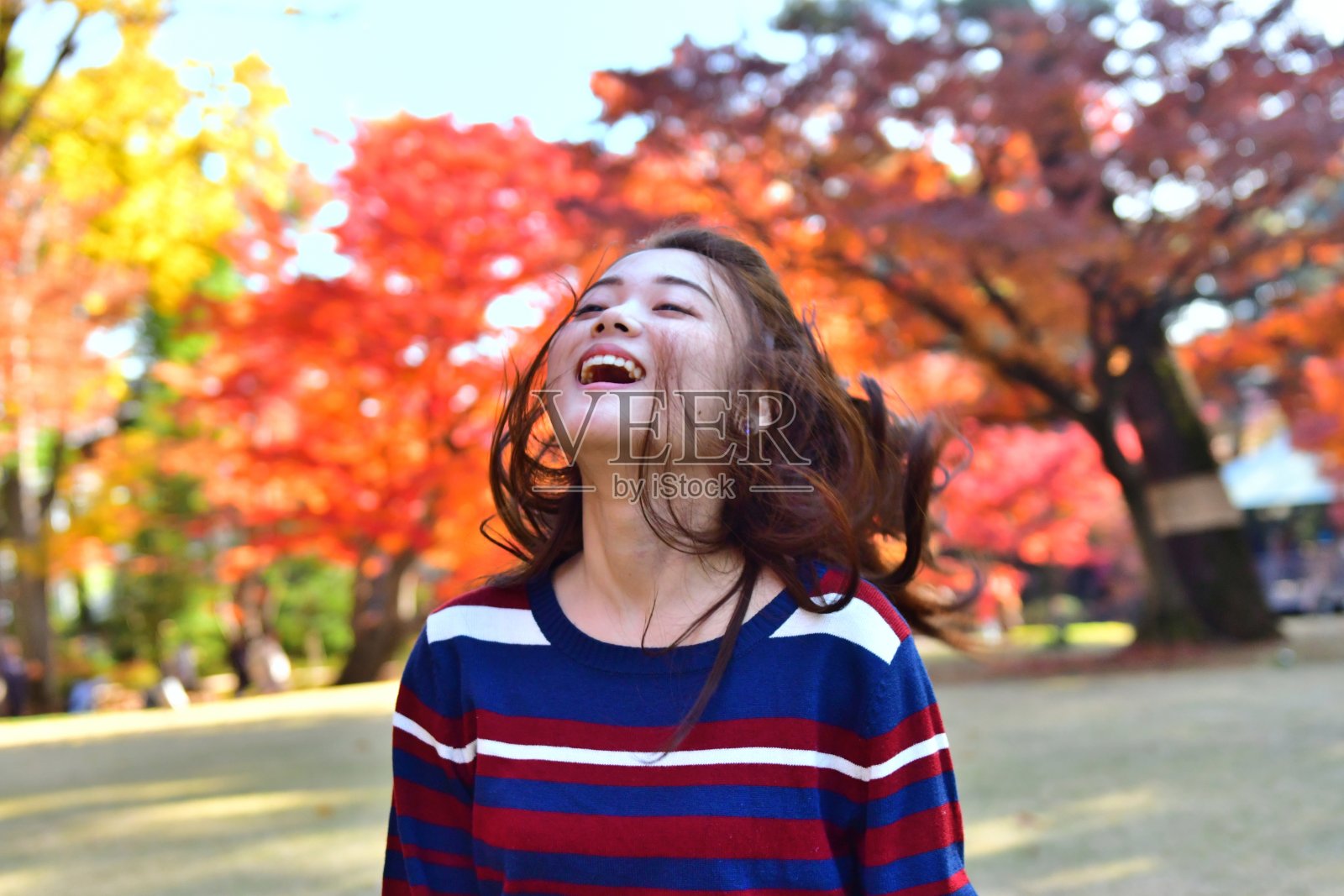 在东京的公园里，一名年轻的日本女子摆弄着她的长发照片摄影图片