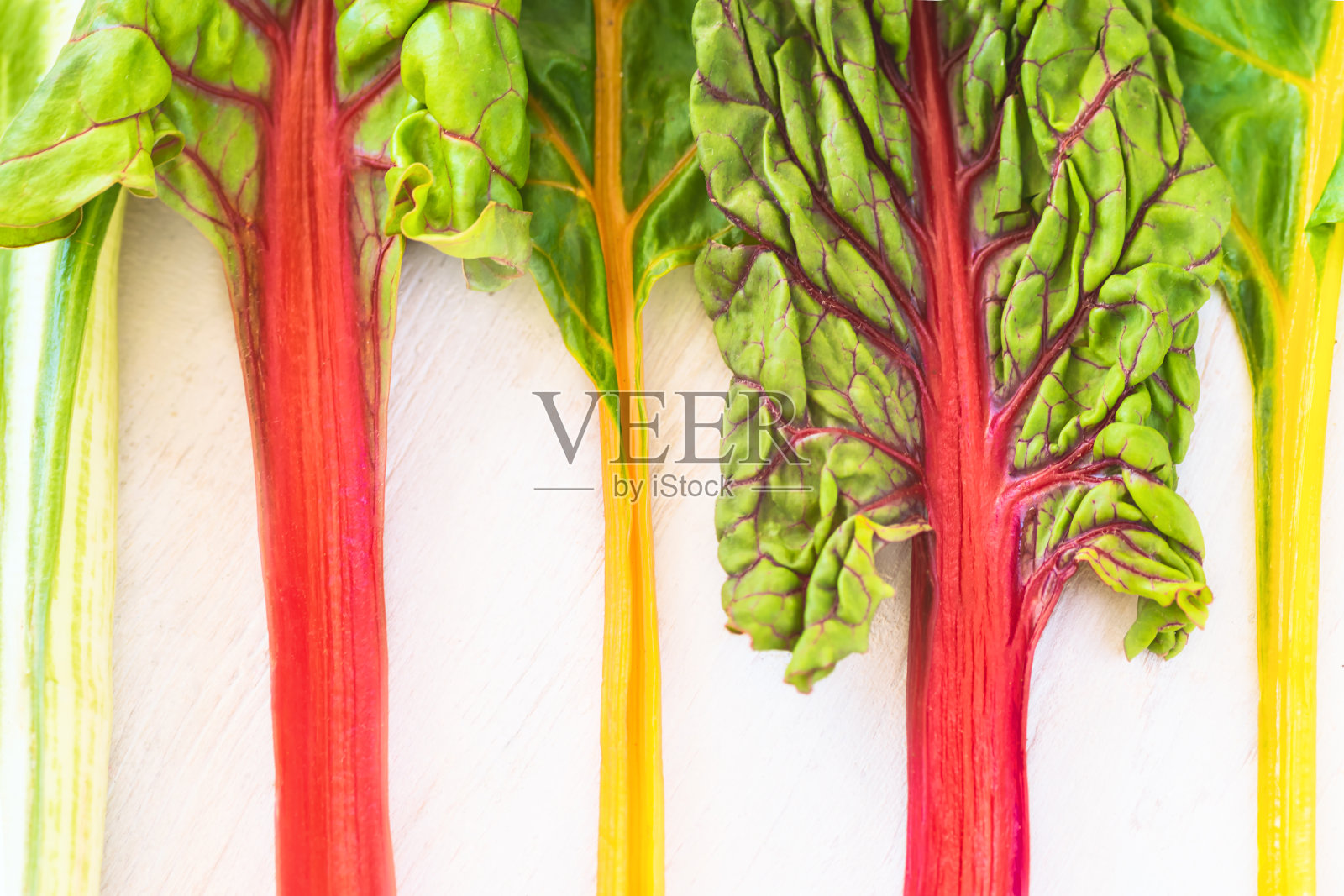 彩色的新鲜甜菜叶在白色木质纹理背景上照片摄影图片