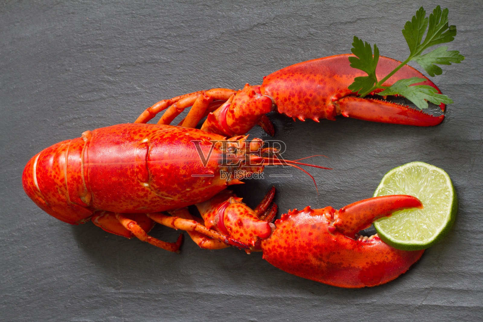 红龙虾配欧芹和青柠爪在黑石有趣的海鲜概念照片摄影图片