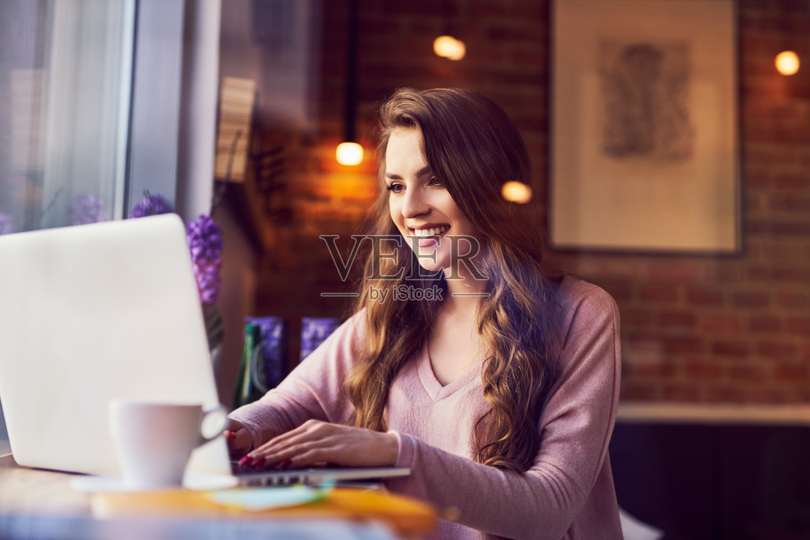 微笑的年轻女子在咖啡馆的笔记本电脑上打字照片摄影图片