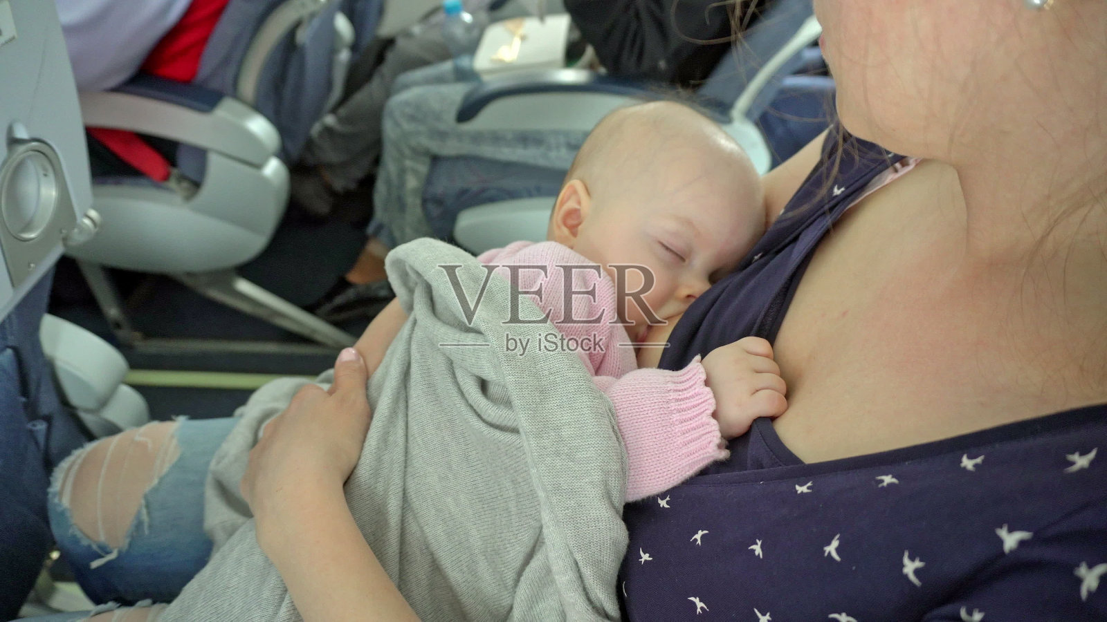 一名妇女在飞机上哺乳她的孩子照片摄影图片