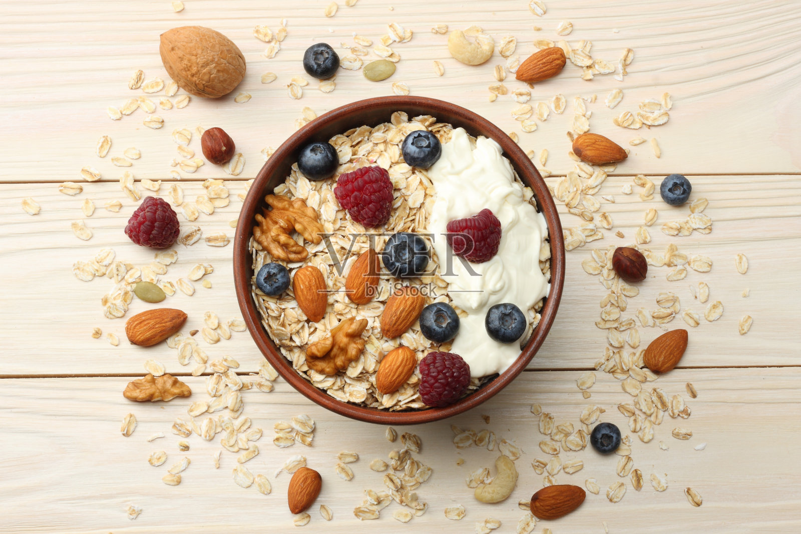 健康的早餐。燕麦片，蓝莓，覆盆子和坚果放在白色的木桌上。顶部视图与复制空间照片摄影图片