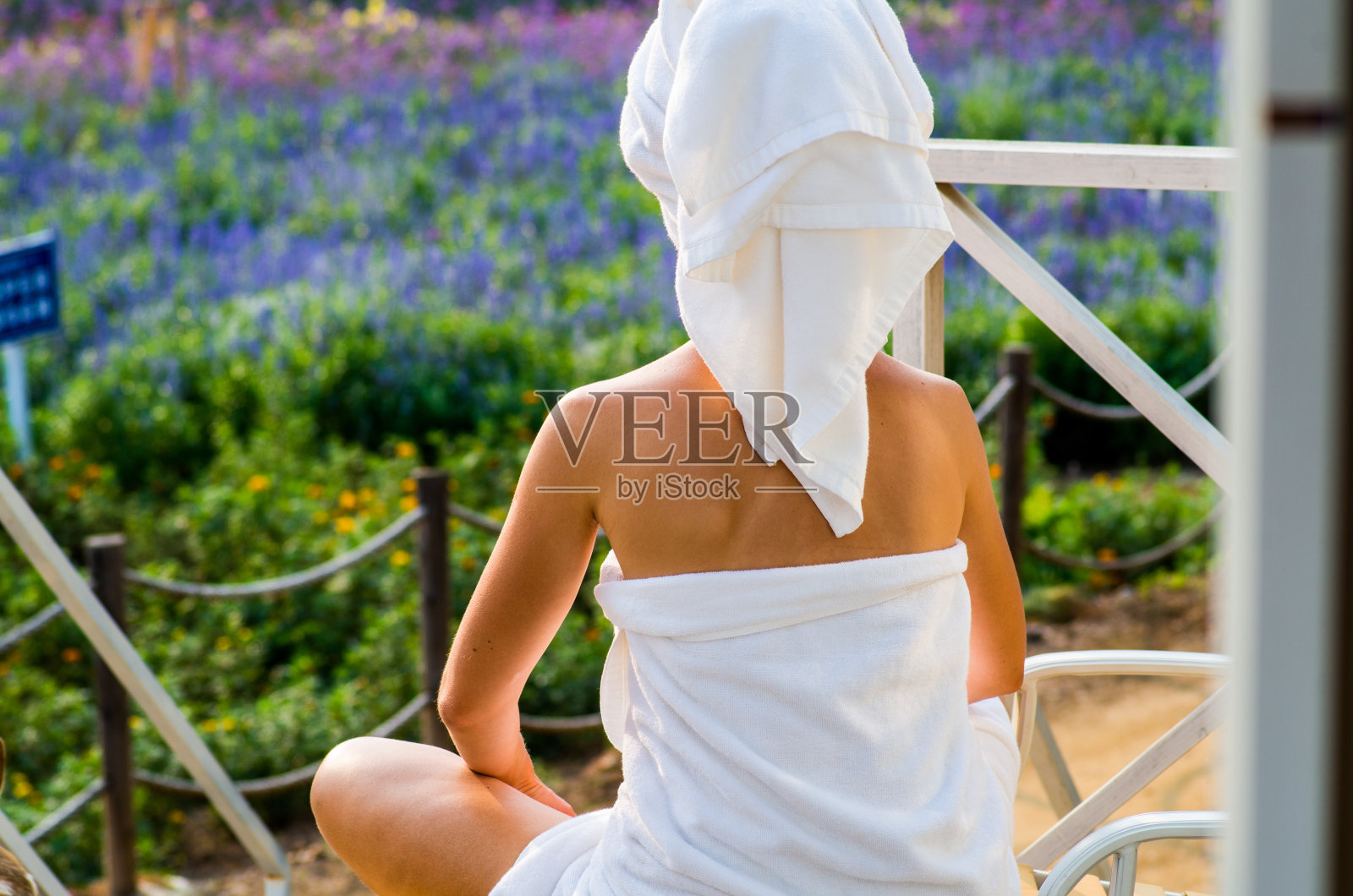 一个裹着浴巾的女人正坐在露台的休息室里照片摄影图片