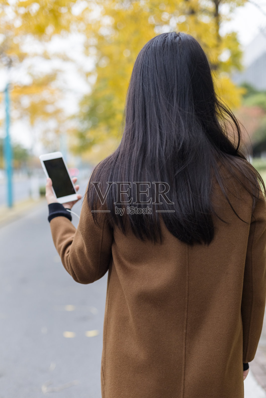 女人在城市街道上拿着智能手机的后视图照片摄影图片