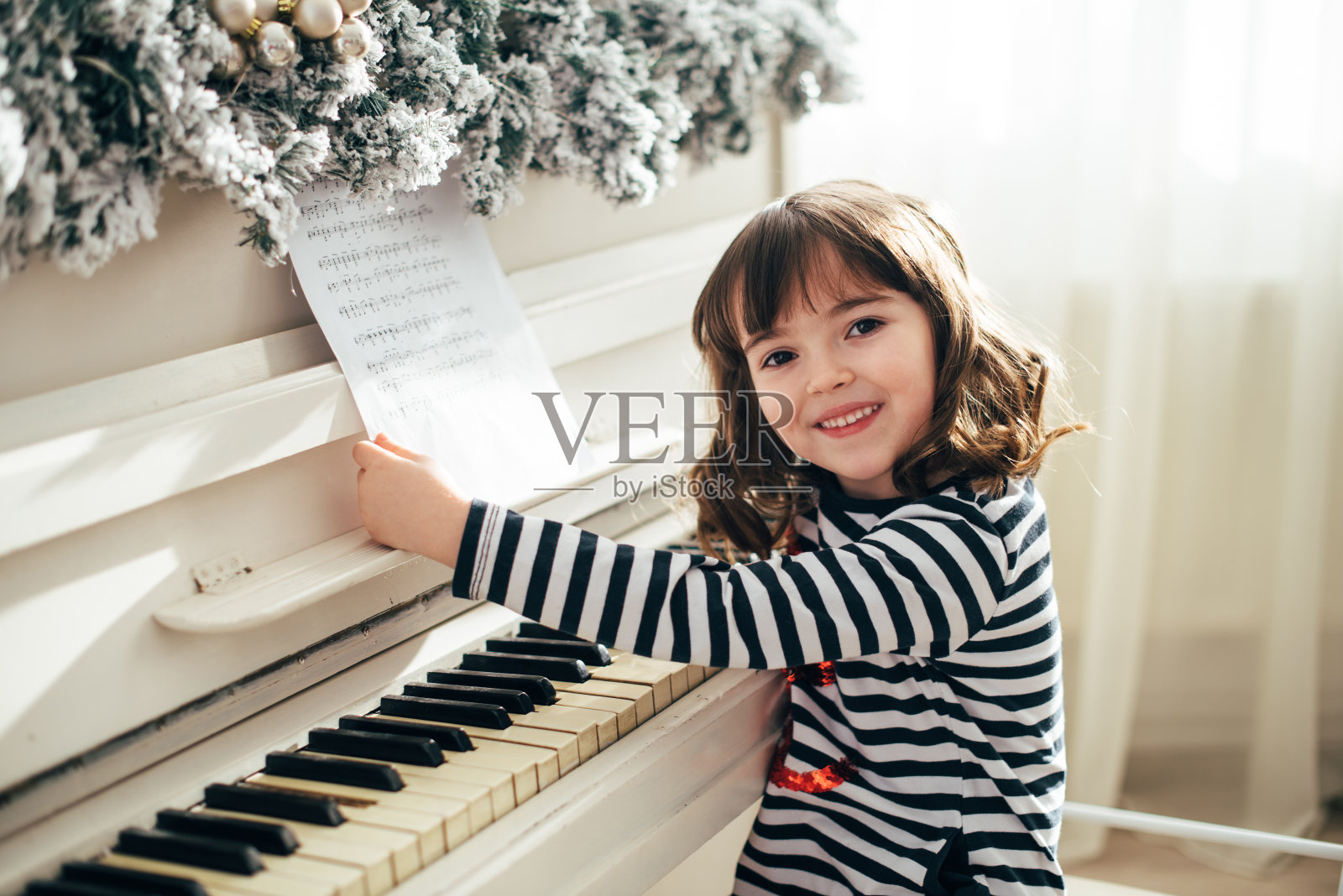 一个可爱的女孩坐在一架白色的钢琴前照片摄影图片