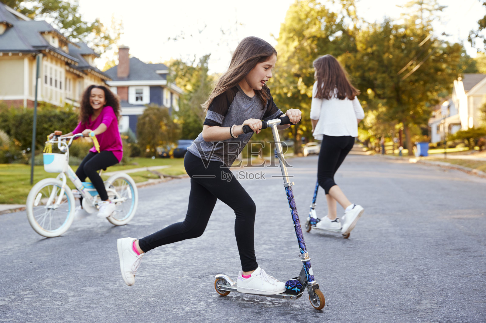 女孩们在街上骑着摩托车和自行车玩耍，特写照片摄影图片