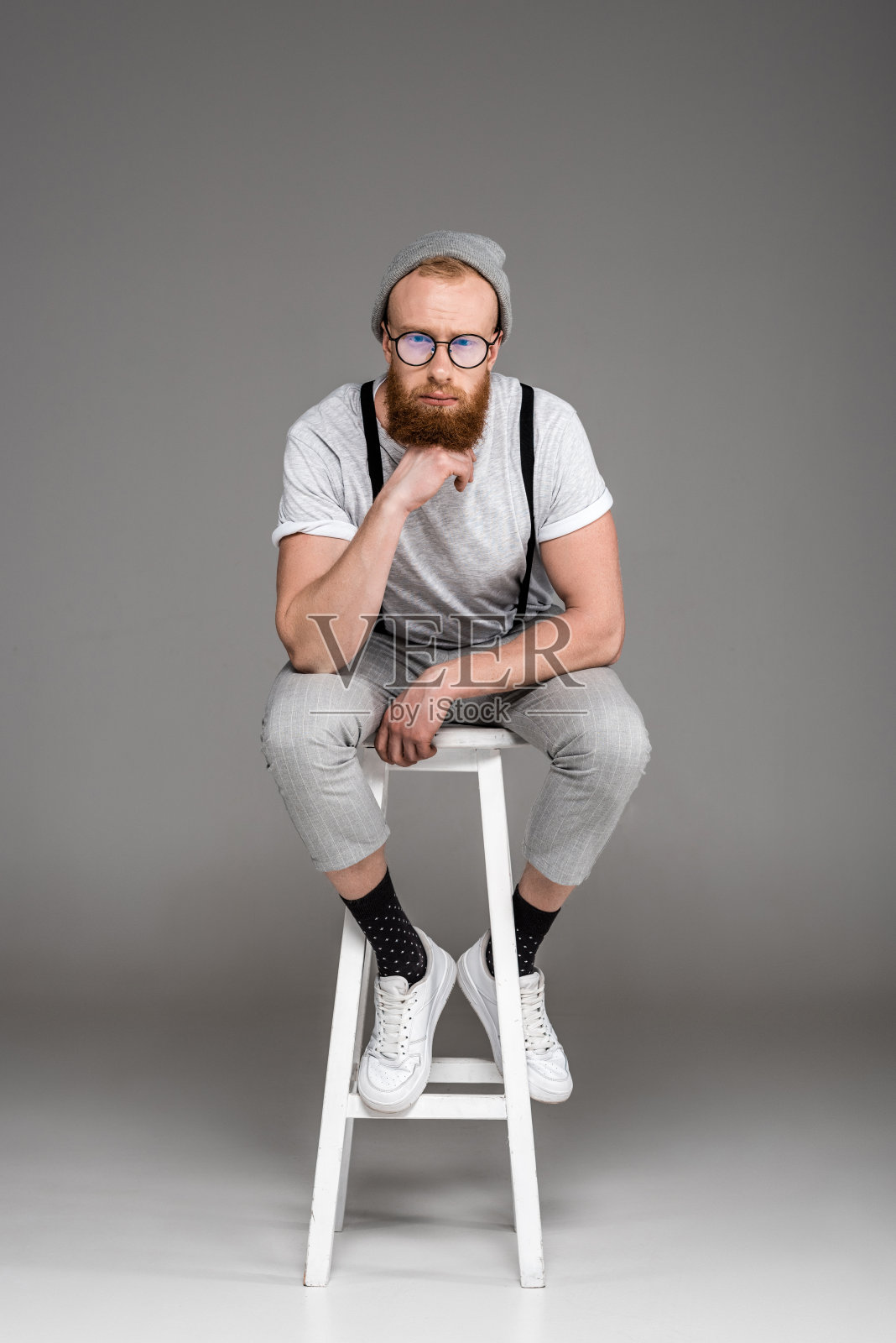 戴眼镜、留胡子的时髦男人坐在凳子上照片摄影图片