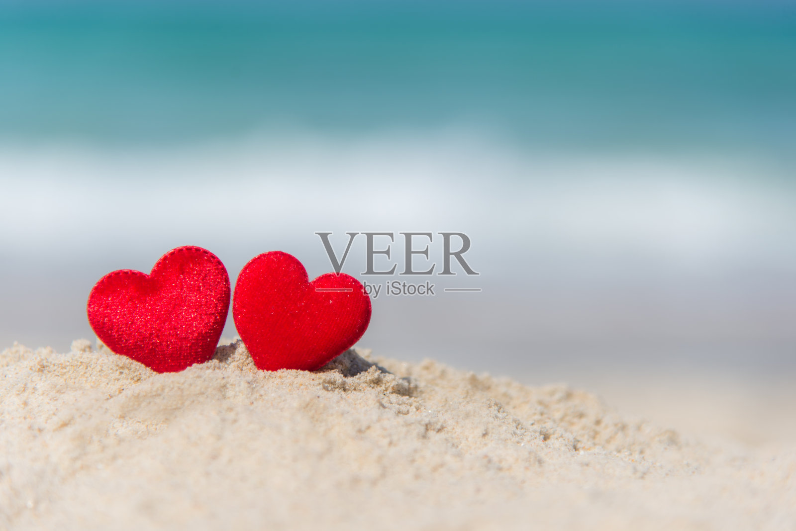 夏日海滩上的两颗红心。情人节。照片摄影图片