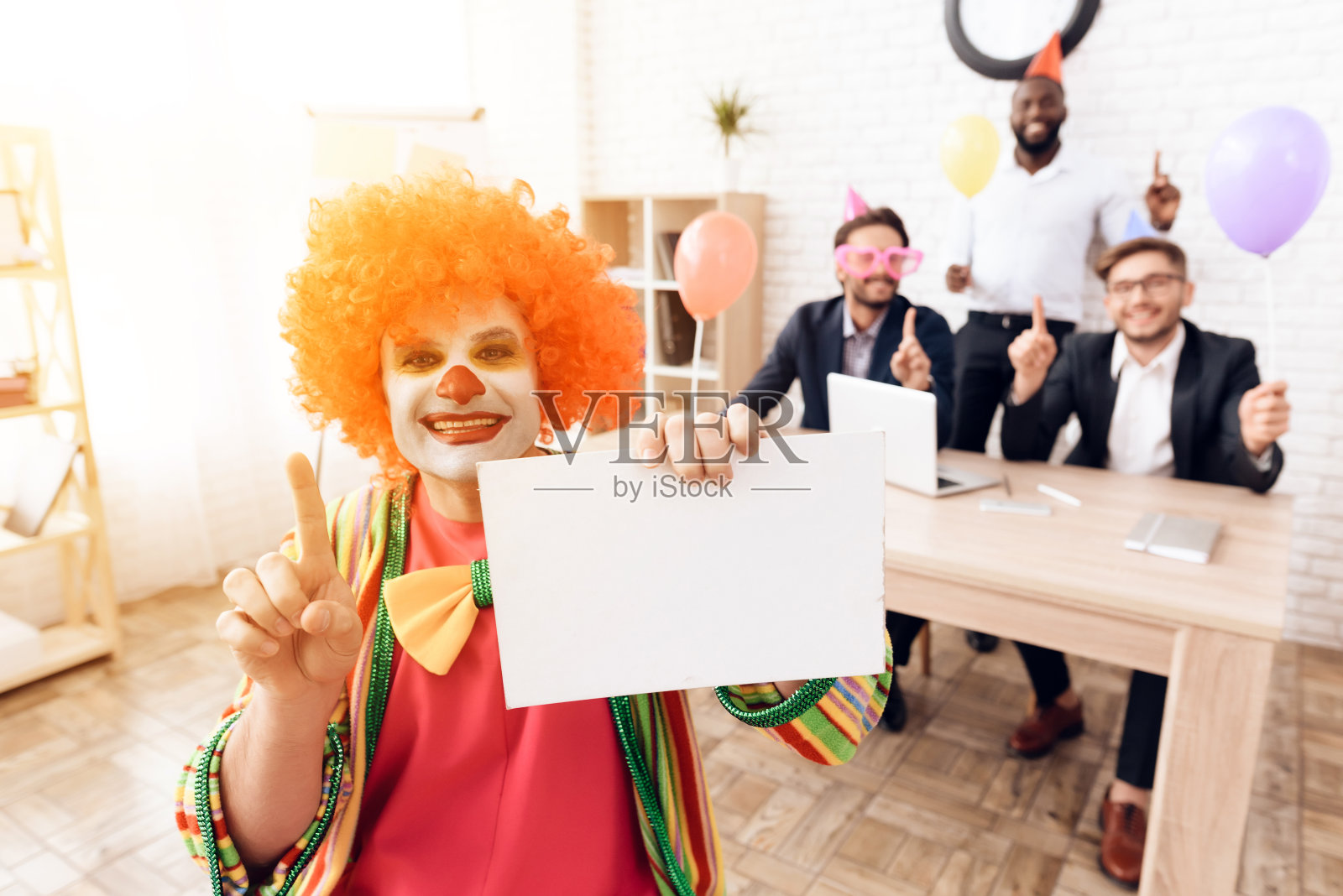 4月1日，一名身穿小丑服、头戴假发的男子坐在商务办公室里。照片摄影图片