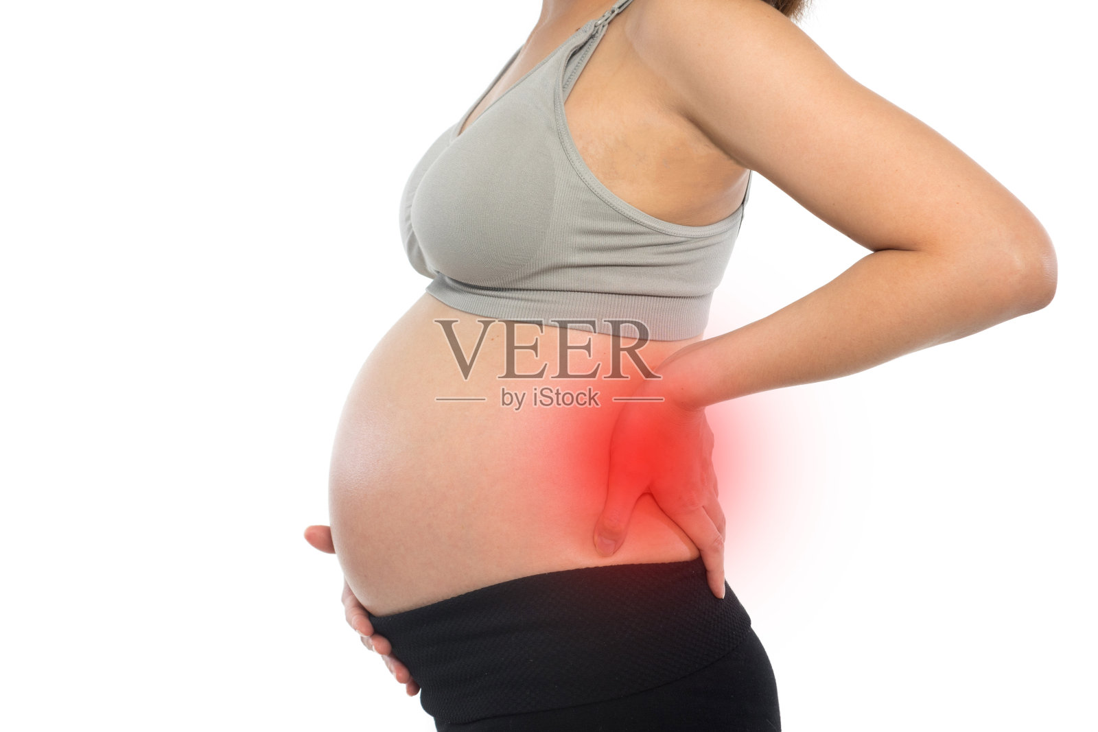 一名孕妇在白色的背景下按摩她的背部，感到强烈的疼痛照片摄影图片