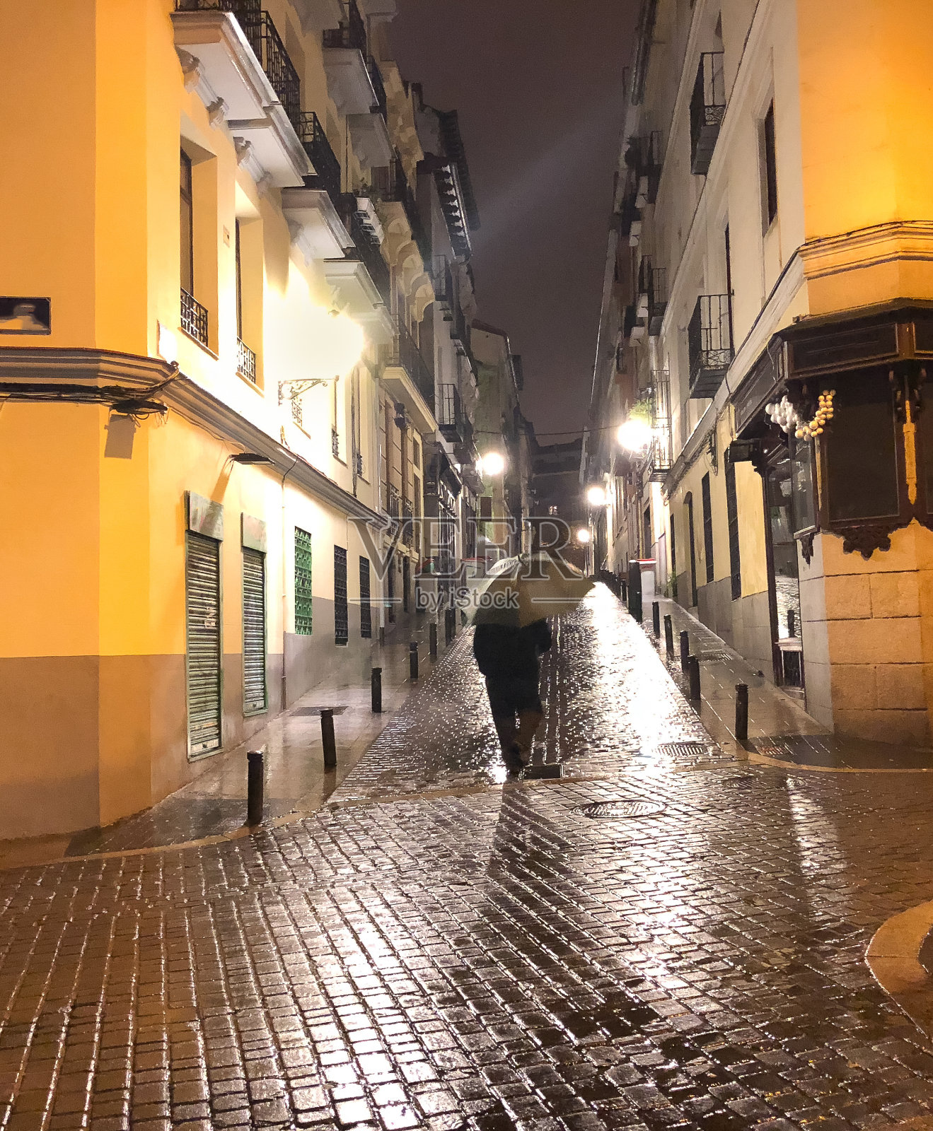 一个在雨夜打着伞走在小巷里的人照片摄影图片