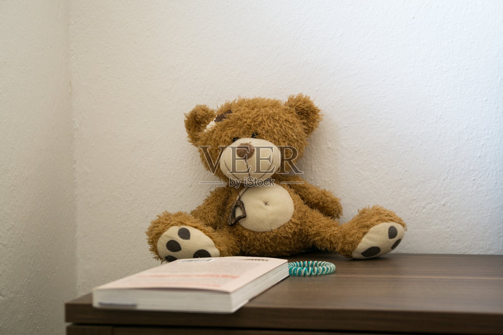 床头桌上放着玩具熊和书。照片摄影图片