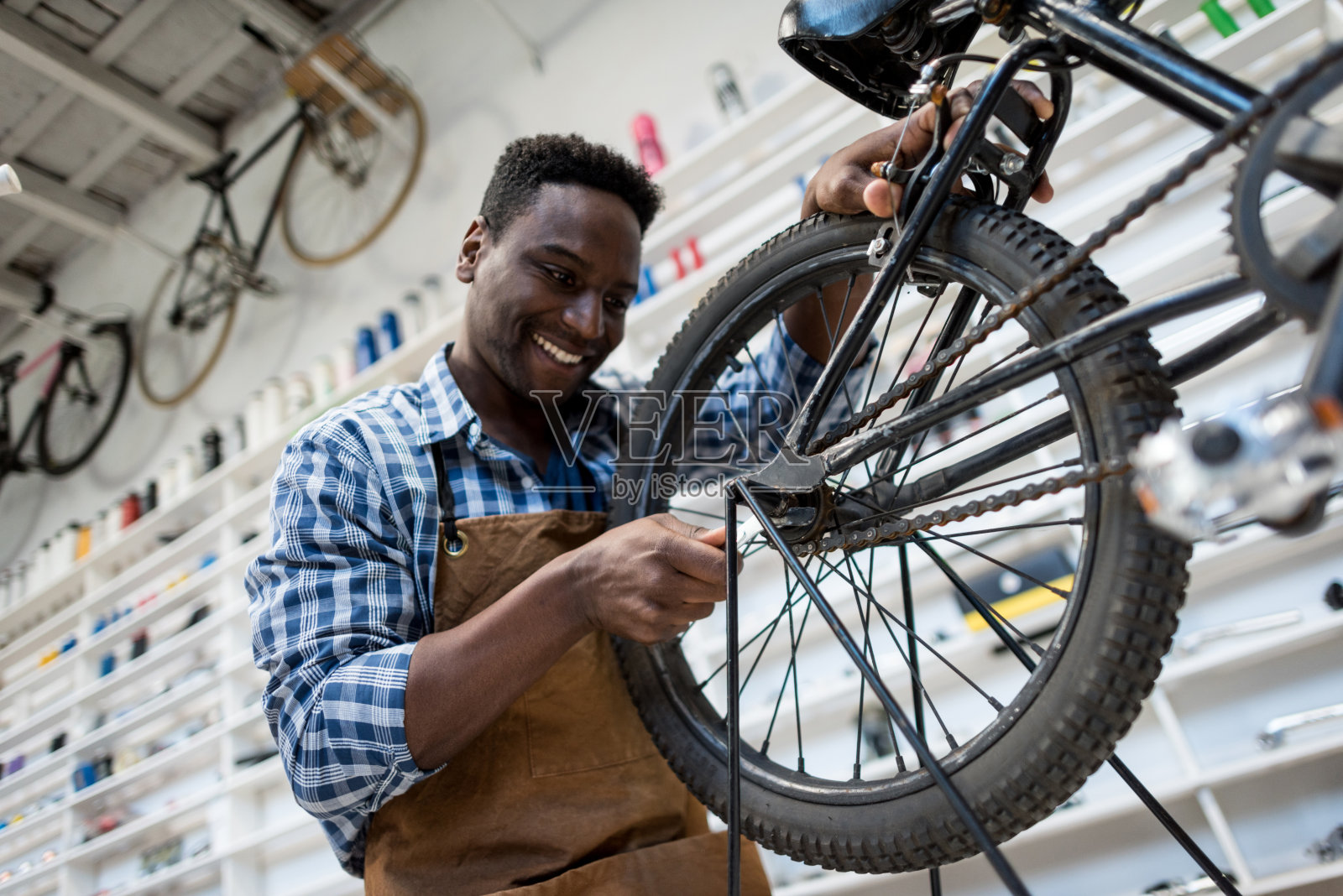 一名拉丁美洲男子在一家自行车修理店修自行车，看起来很开心照片摄影图片