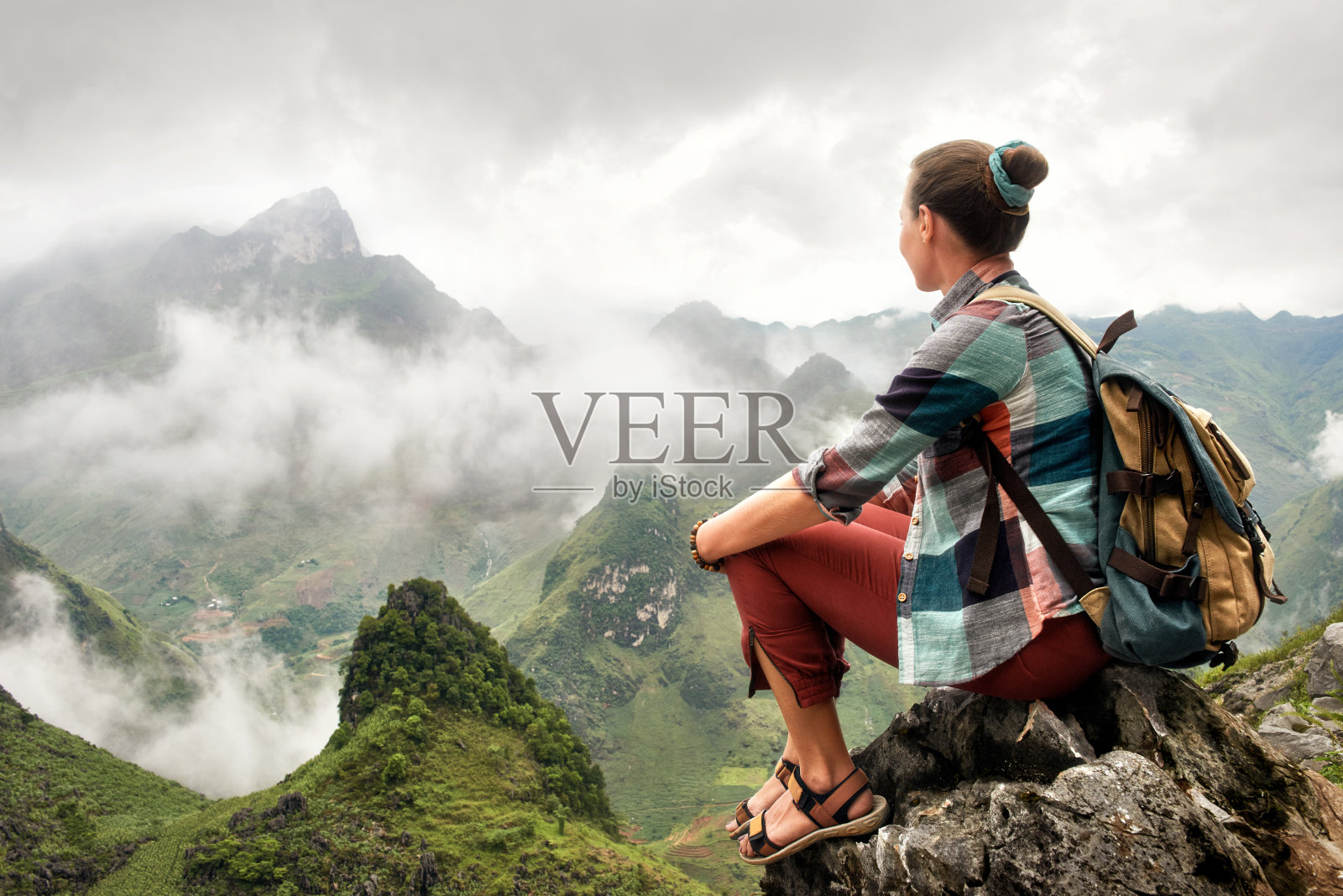 徒步旅行者坐在山顶欣赏雾蒙蒙的山景。照片摄影图片