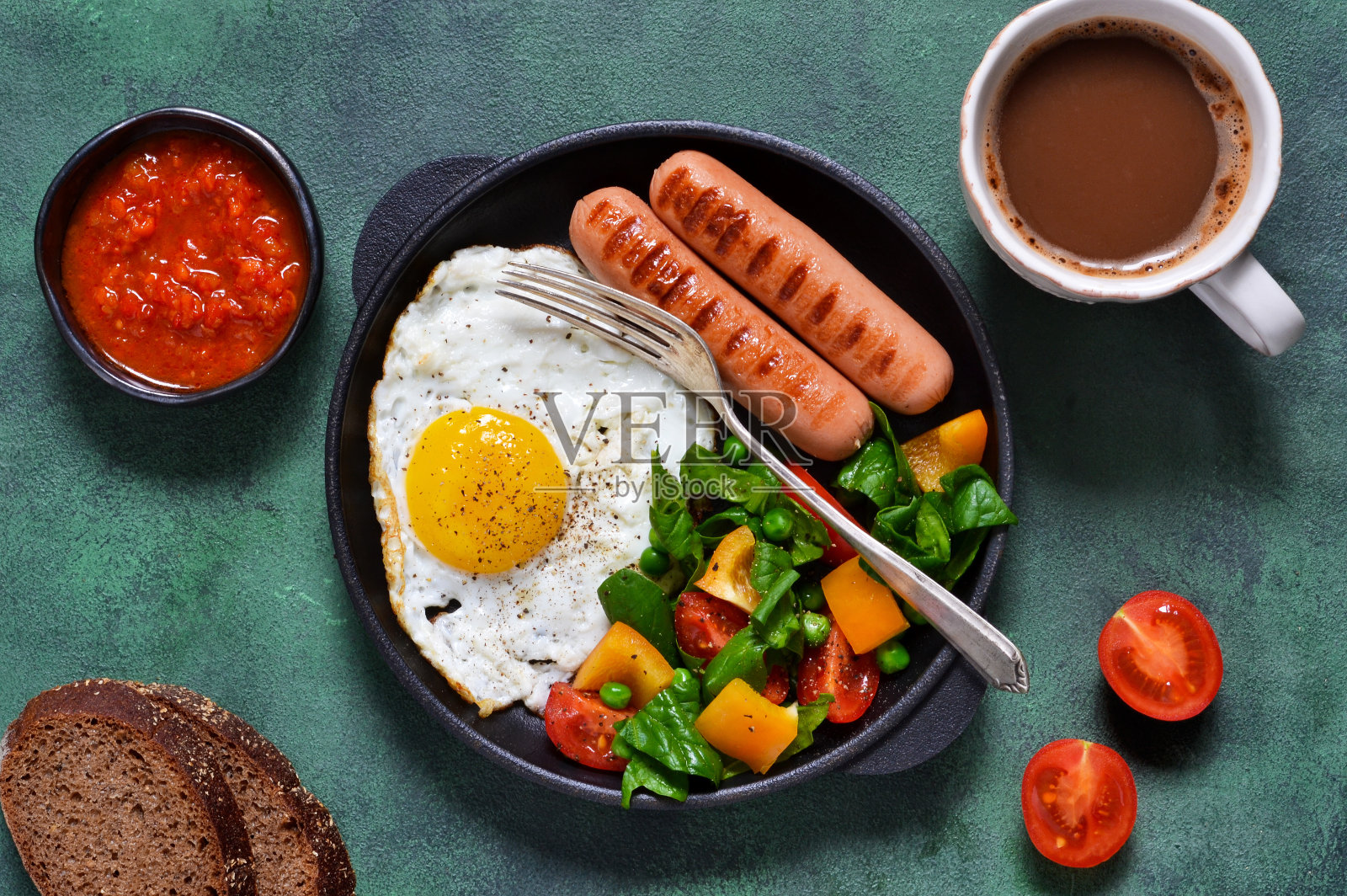 早上好!早餐有香肠、鸡蛋、沙拉和番茄酱，还有一杯咖啡，背景是绿色的混凝土。照片摄影图片