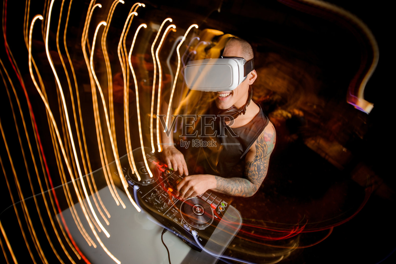 戴着虚拟现实眼镜的微笑DJ。照片摄影图片