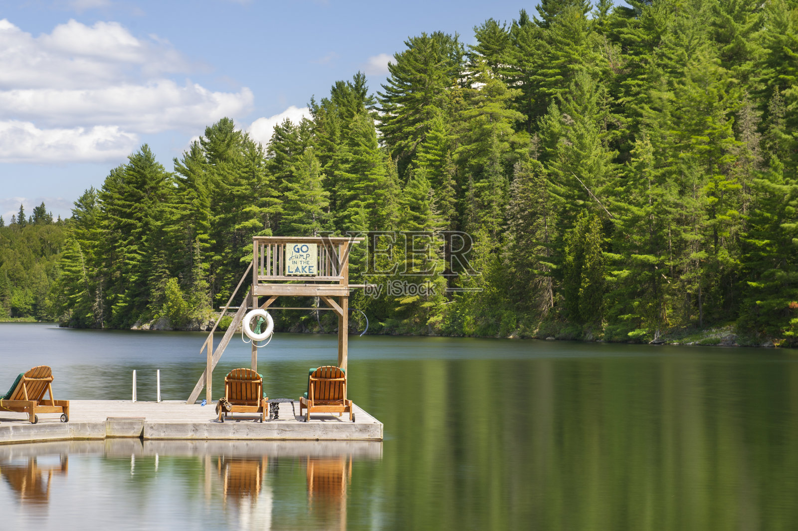 在加拿大，一个码头上的木制蹦床面对着一个平静的湖照片摄影图片
