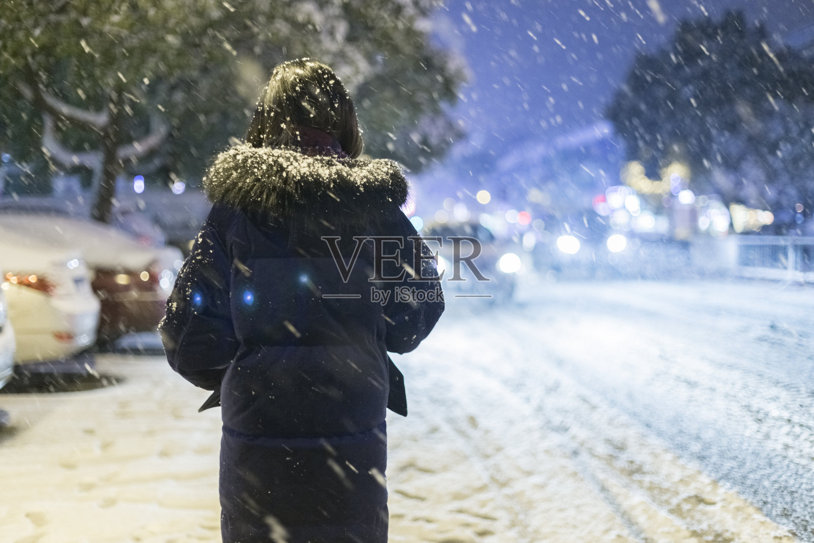 后视图的女人走在街上的晚上在雪照片摄影图片