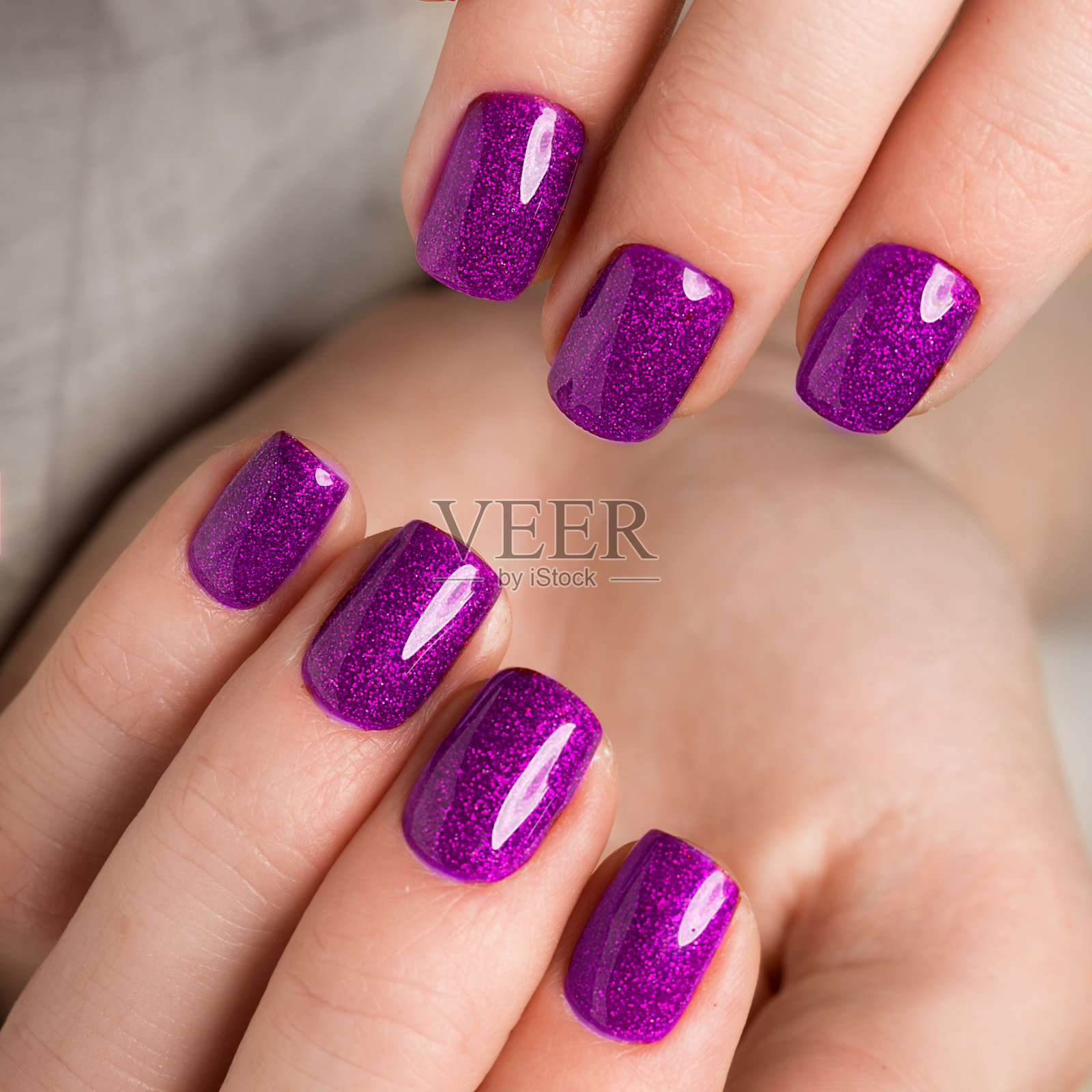 鲜艳喜庆的紫色美甲在女性手上。指甲的设计照片摄影图片